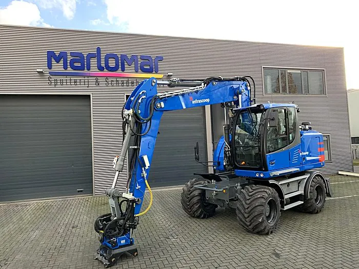 Blauwe mobiele graafmachine bij bedrijfspand